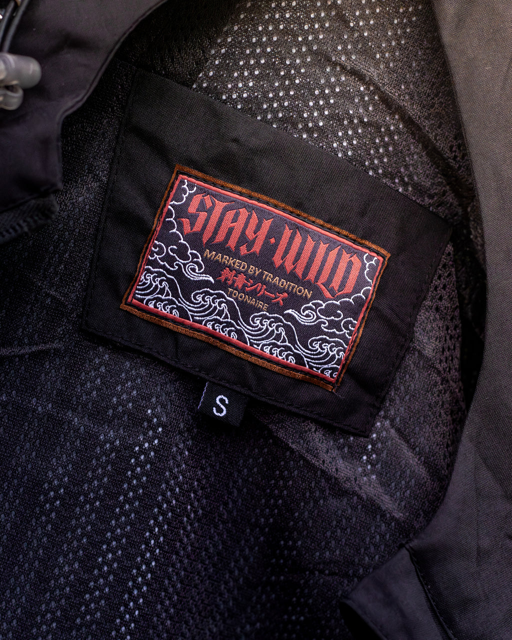 STAY WILD woven label inside Hanya Windbreaker — Marked by Tradition